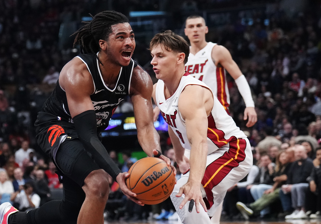 Toronto Raptors' Collin Murray-Boyles (left) drives past Miami Heat's Pelle Larsson (9) during the first period of an NHL game in Ottawa, Thursday, April 9, 2026. (Adrian Wyld/The Canadian Press via AP)