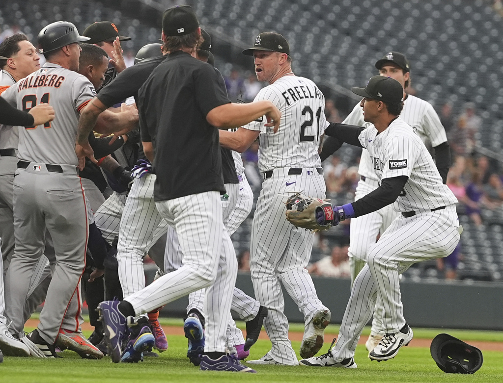 Colorado Rockies pitcher Kyle Freeland (21) is protected by teammates as members of the San Francisco Giants pursue after Freeland exchanged words with the Giants' Rafael Devers in the first inning of a baseball game Tuesday, Sept. 2, 2025, in Denver. (AP Photo/David Zalubowski)