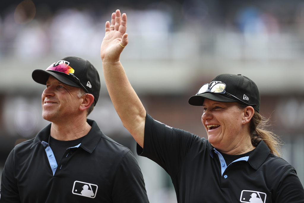 Umpires Chris Guccione, left, and Jen Pawol, right, react to fans in the crowd at the conclusion of the first baseball game of a doubleheader between the Atlanta Braves and Miami Marlins, Saturday, Aug. 9, 2025, in Atlanta. (AP Photo/Colin Hubbard)