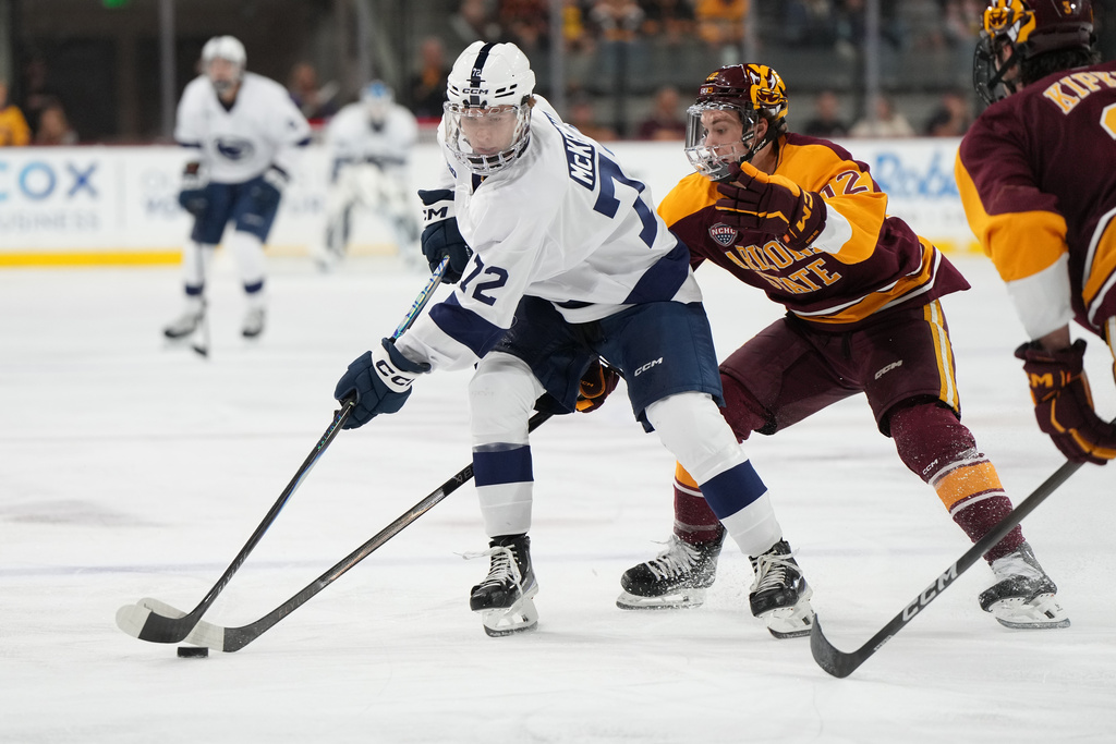 Penn State left winger Gavin McKenna, left, carries the puck in front of Arizona State Cullen Potter (12) during the second period of an NCAA college hockey game, Friday, Oct. 3, 2025, in Tempe, Ariz. (AP Photo/Rick Scuteri)