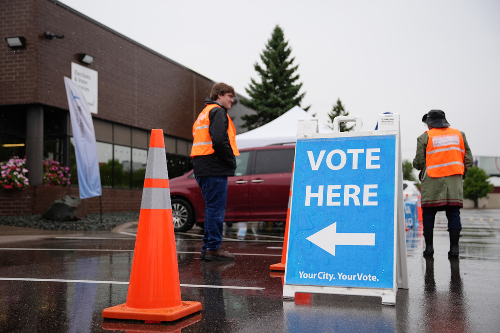 Poll workers stand outside despite rainy weather on the first day of early voting in Minnesota at the Elections & Voter Services building, Friday, Sept. 18, 2026, in Minneapolis. (AP Photo/Ellen Schmidt)