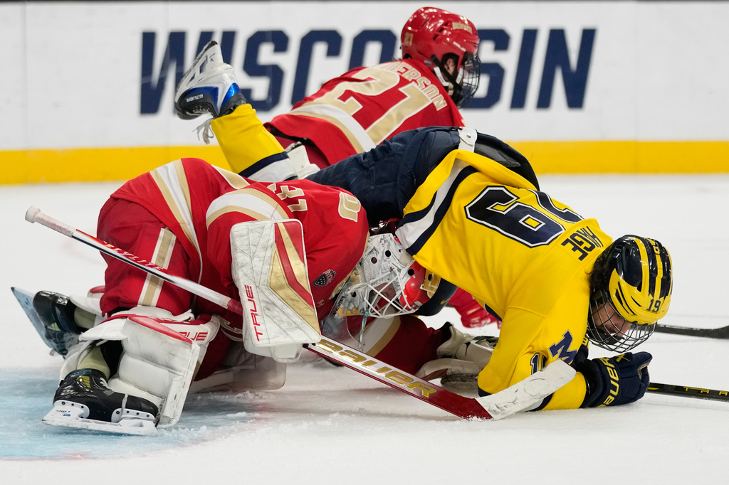 Michigan forward Michael Hage (19) falls on Denver goaltender Johnny Hicks (31) in the second period of a semifinal game of the NCAA Frozen Four men's college hockey tournament Thursday, April 9, 2026, in Las Vegas. (AP Photo/John Locher)