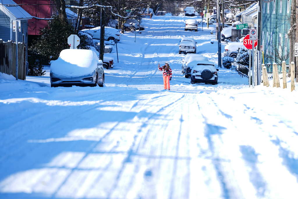A woman takes a photo on a snow-covered street, Sunday, Feb 1, 2026, in Charlotte, N.C. (AP Photo/Matt Kelley)