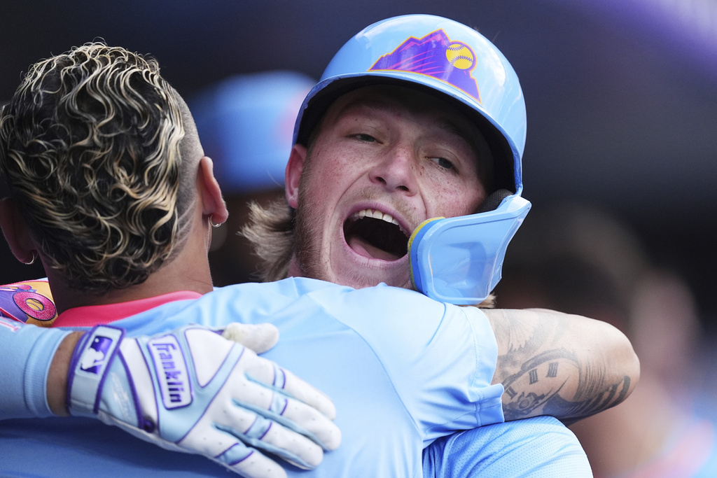 Colorado Rockies' Orlando Arcia, front, hugs Hunter Goodman as he returns to the dugout after hitting a solo home run off Arizona Diamondbacks starting pitcher Brandon Pfaadt in the first inning of a baseball game Friday, Aug. 15, 2025, in Denver. (AP Photo/David Zalubowski)
