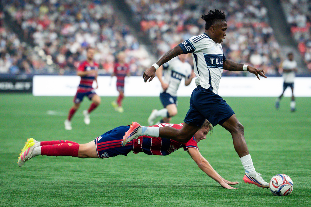 Vancouver Whitecaps' Edier Ocampo, right runs with the ball as FC Dallas' Nolan Norris dives during the first half of an MLS soccer match in Vancouver, British Columbia, Saturday, Aug. 22, 2026. (Ethan Cairns/The Canadian Press via AP)