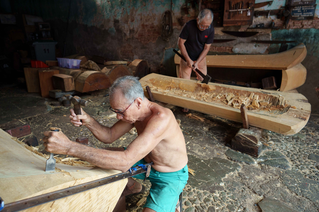 Traditional Chinese coffin maker Goh Khuay Par, left, and his brother Goh Khuay Hou, carve Mei Hua coffins at their workshop in Muar, Johor state, Malaysia, Wednesday, July. 29, 2026. (AP Photo/Vincent Thian)