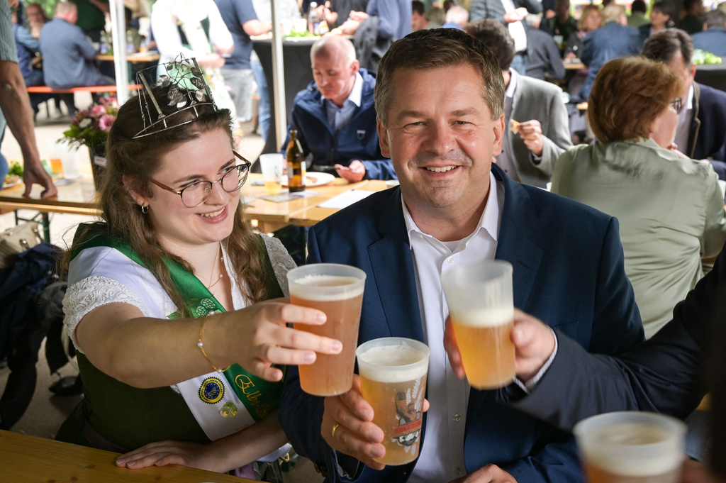 Sven Schulze, the governor of Saxony-Anhalt state and the center-right Christian Democratic Union's top candidate in the upcoming state election, poses with a beer near Hop Queen Katharina at the Hop Day Photo in Beesenstedt, Germany, Aug. 19, 2026. (Heiko Rebsch/dpa via AP)