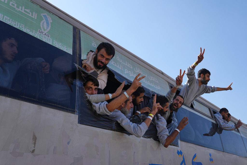 Freed Palestinian prisoners wave from a bus as they arrive in the Gaza Strip after their release from Israeli jails under a ceasefire agreement between Hamas and Israel, in Khan Younis, southern Gaza Strip, Monday, Oct. 13, 2025. (AP Photo/Jehad Alshrafi)