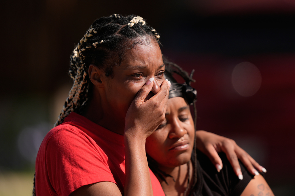 People comfort each other outside the scene of a mass shooting, Sunday, April 19, 2026, in Shreveport, La. (AP Photo/Gerald Herbert)