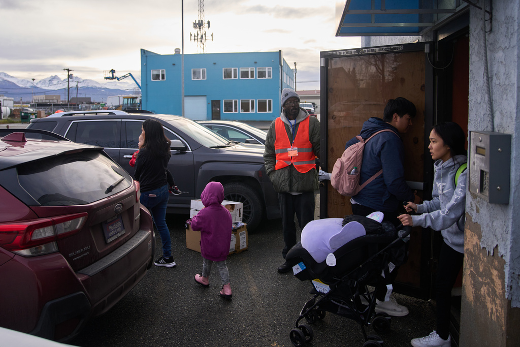 At left, Chantal Snyder, who lost her home in Kwigillingok, Alaska due to Typhoon Halong, walks with her son Amonte Feagle and daughter Octavia Feagle as Quent Dock, of Kipnuk, and Snyder's sister Dolores Snyder bring out supplies they were given at a donation event for evacuees put on by the Shiloh Community Housing and World Vision, Friday, Oct. 31, 2025, in Anchorage, Alaska. (AP Photo/Lindsey Wasson)