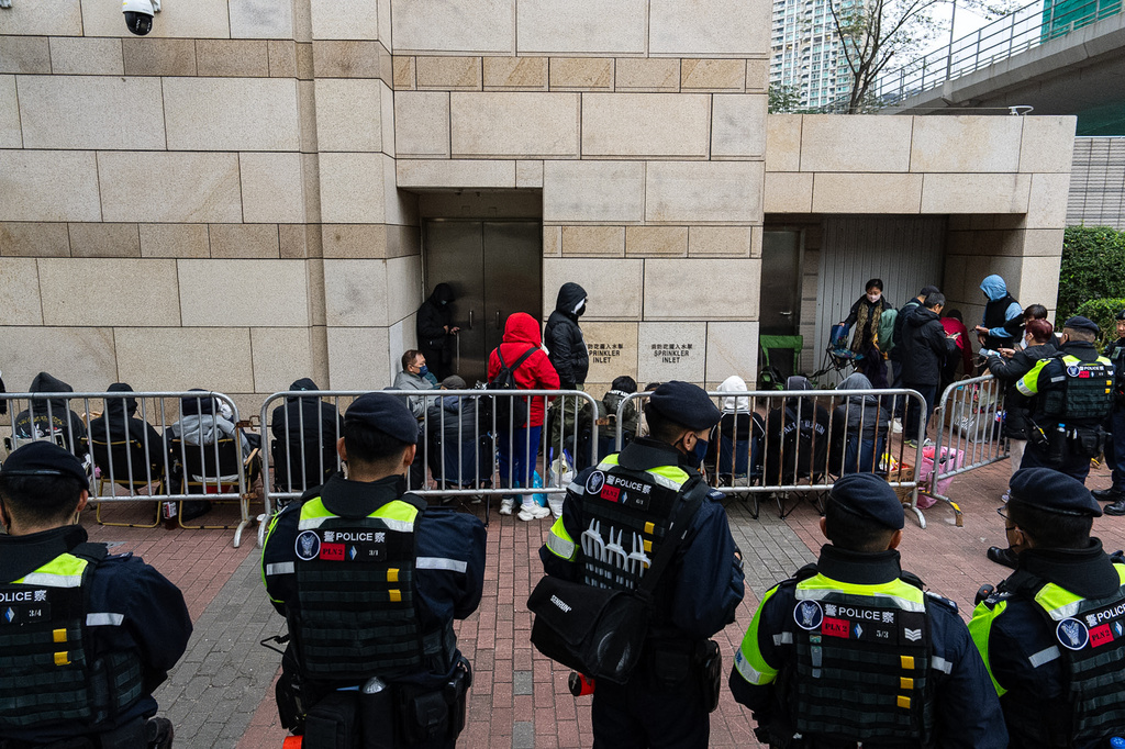 Police officers stand guard as people wait outside the West Kowloon Magistrates' Courts to attend a trial under a China-imposed national security law on Thursday, Jan. 22, 2026, in Hong Kong. (AP Photo/Chan Long Hei)