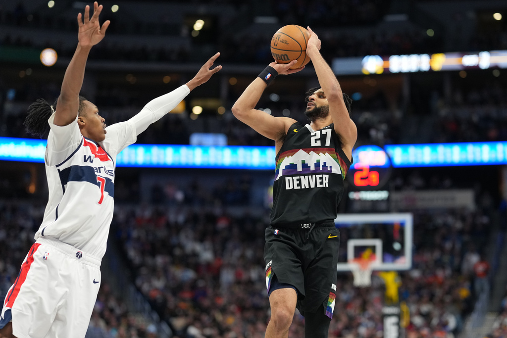 Denver Nuggets guard Jamal Murray, right, looks to shoot for a basket over Washington Wizards guard Bub Carrington, left, in the second half of an NBA basketball game Saturday, Jan. 17, 2026, in Denver. (AP Photo/David Zalubowski)