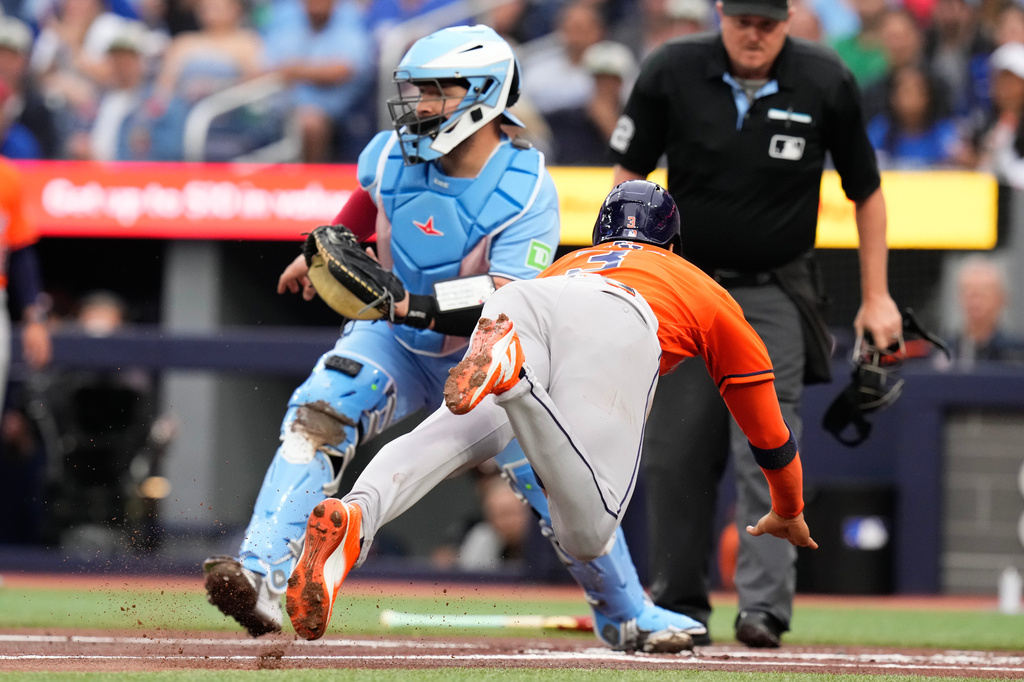 Houston Astros' Jeremy Pena (3) dives into home plate to score in front of Toronto Blue Jays catcher Alejandro Kirk (30) during the first inning of a baseball game in Toronto on Wednesday, June 24, 2026. (Chris Young/The Canadian Press via AP)