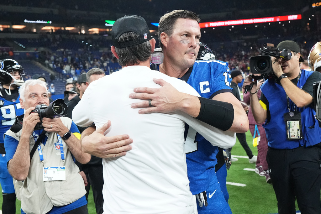 San Francisco 49ers head coach Kyle Shanahan, middle left, hugs Indianapolis Colts quarterback Philip Rivers after an NFL football game, Monday, Dec. 22, 2025, in Indianapolis. (AP Photo/AJ Mast)