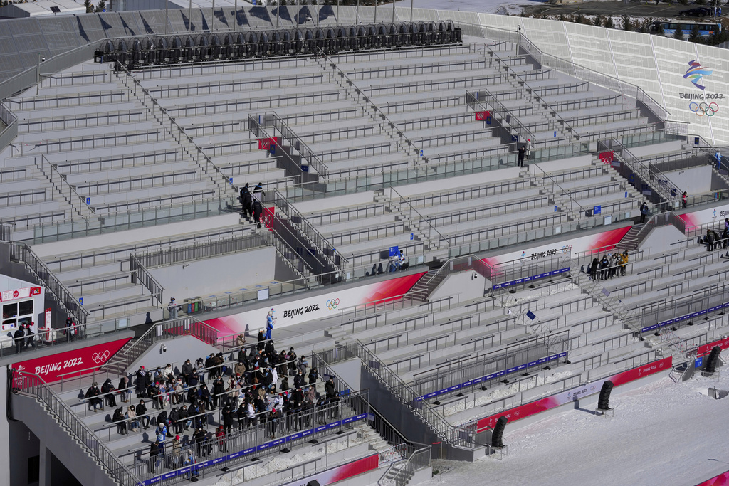 FILE- People watch the men's normal hill individual ski jumping trial round in a nearly empty Zhangjiakou National Ski Jumping Centre at the 2022 Winter Olympics, Feb. 5, 2022, in Zhangjiakou, China. (AP Photo/Andrew Medichini, File)