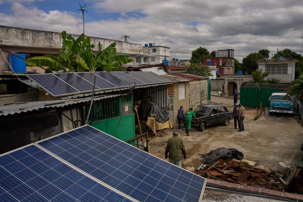 Solar panels cover the roof at the home of Felix Jose Morfi where mechanics push his broken down Lada car in Regla, Havana province, Cuba, Thursday, Jan. 29, 2026. (AP Photo/Ramon Espinosa)