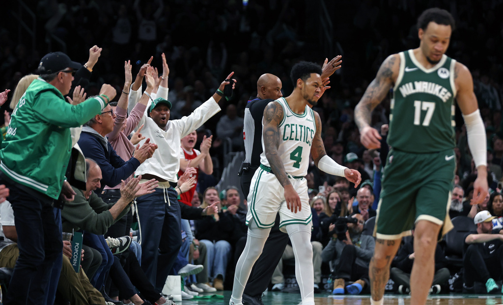 Fans, left, react after Boston Celtics guard Anfernee Simons (4) hit a 3-point basket as the buzzer sounded for the end of the first quarter of an NBA basketball game against the Milwaukee Bucks, Sunday, Feb 1, 2026, in Boston. (AP Photo/Jim Davis)