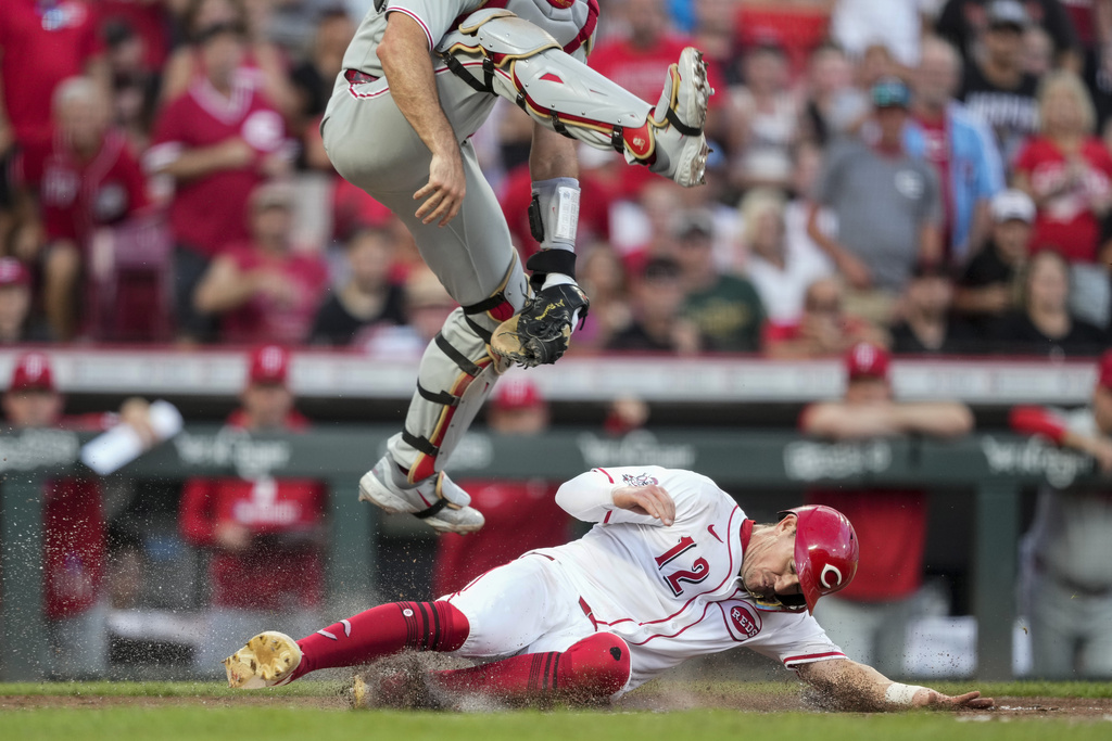 Cincinnati Reds' Austin Hays slides safe at home under leaping Philadelphia Phillies catcher J.T. Realmuto on a single hit by Noelvi Marte during the sixth inning of a baseball game Wednesday, Aug. 13, 2025, in Cincinnati. (AP Photo/Carolyn Kaster)