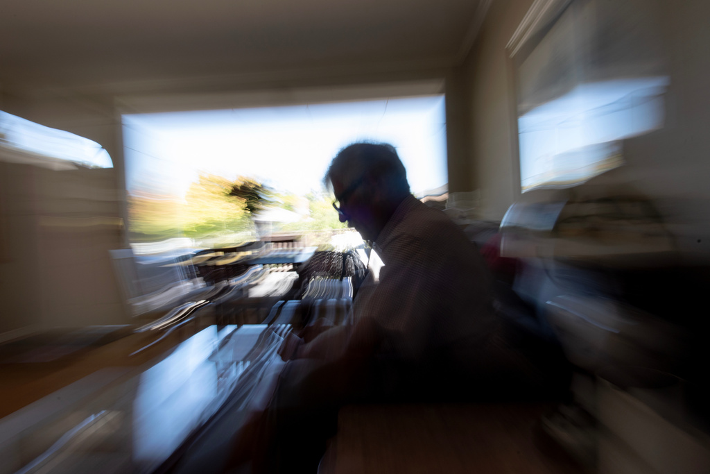 Christy Morrill, who lost decades of memories to autoimmune encephalitis, sits at his home while looking through photos on his phone, Tuesday, Aug. 19, 2025, in San Carlos, Calif. (AP Photo/David Goldman)