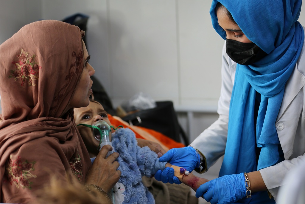 Latifa Bakkar attempts to give oxygen to her severely malnourished 2½-year-old son, Abu Bakar, as a nurse inserts an intravenous cannula into his arm at Indira Gandhi Children's Hospital in Kabul, Afghanistan, Sunday, Feb. 15, 2026. (AP Photo/Siddiqullah Alizai)