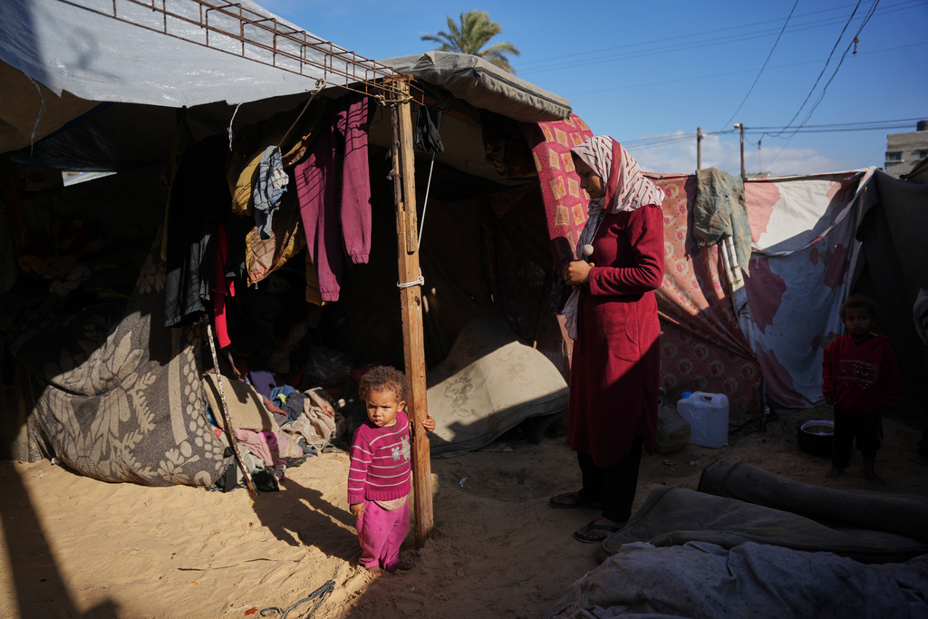 Siraj Obeid, 27, looks at her daughter as they stand in their tent in a makeshift camp for displaced Palestinians in Deir al-Balah, central Gaza Strip, Saturday, Dec. 27, 2025. (AP Photo/Abdel Kareem Hana)