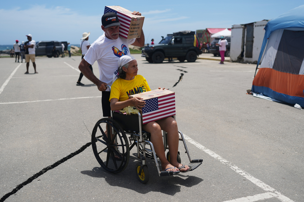 People affected by the earthquakes carry U.S. humanitarian aid after receiving it in La Guaira, Venezuela, Wednesday, July 8, 2026. (AP Photo/Ariana Cubillos)