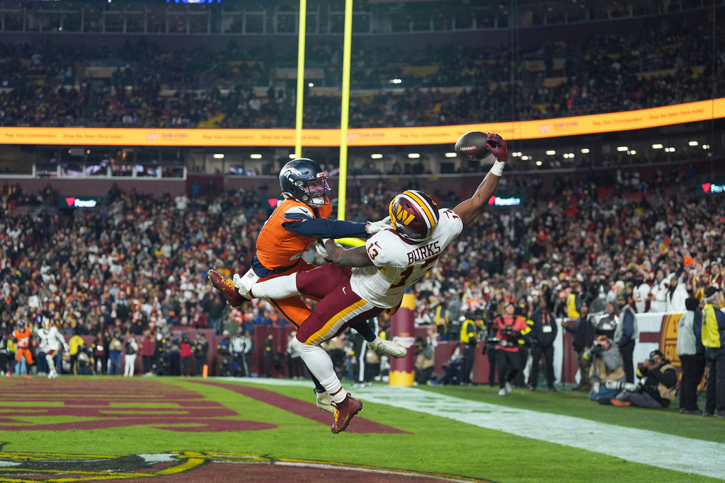 Washington Commanders wide receiver Treylon Burks (13) catches a touchdown pass as Denver Broncos cornerback Riley Moss, left, defends during the second half of an NFL football game Sunday, Nov. 30, 2025, in Landover, Md. (AP Photo/Stephanie Scarbrough)