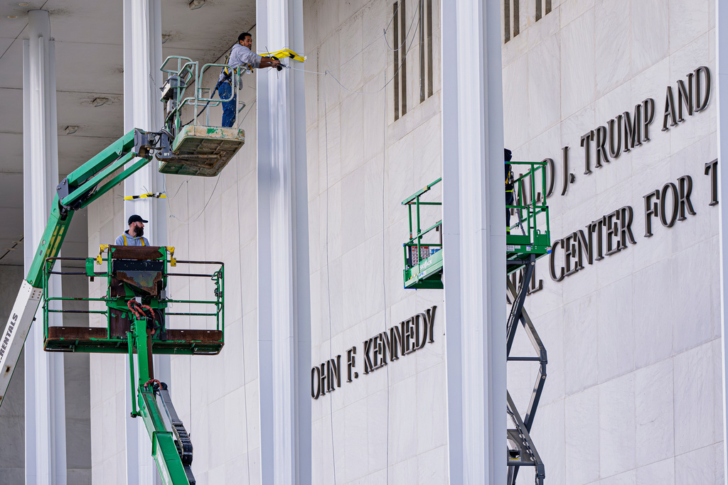 Workers add President Donald Trump's name to the John F. Kennedy Memorial Center for the Performing Arts, after a Trump-appointed board voted to rename the institution, in Washington, Friday, Dec. 19, 2025. (AP Photo/J. Scott Applewhite)
