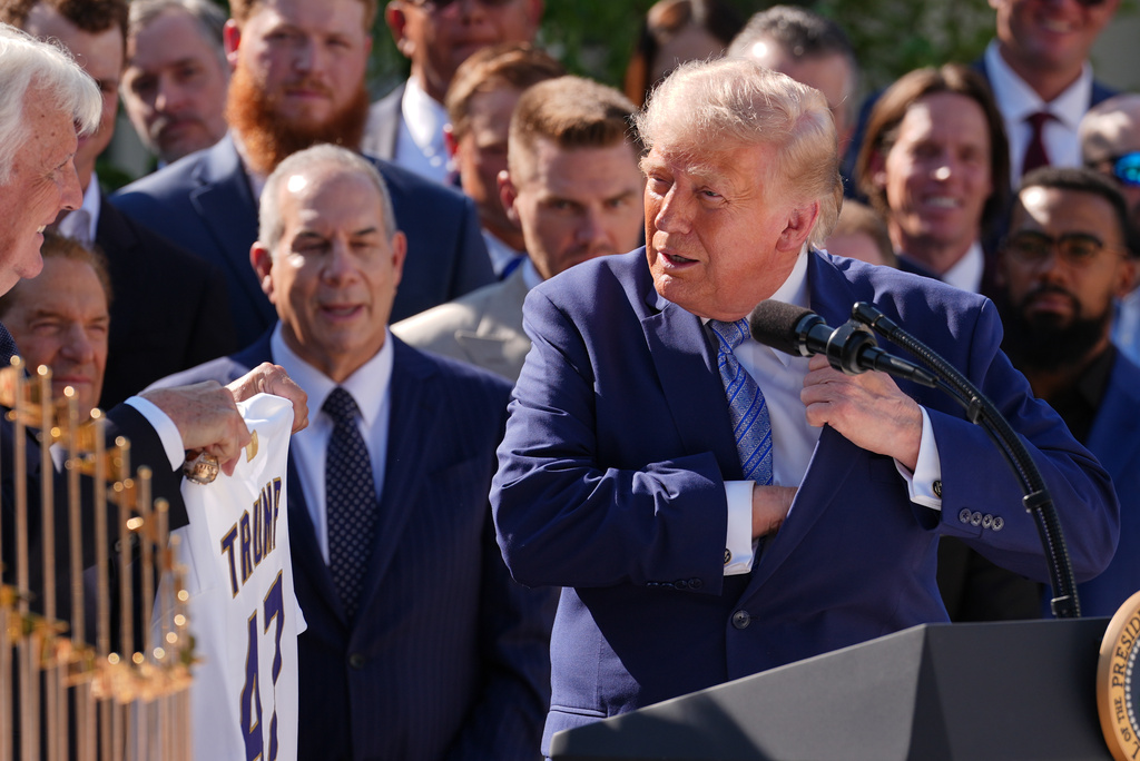 President Donald Trump tucks a Los Angeles Dodgers Championship Ring into his jacket pocket, as owner Mark Walter, left, looks on, during an event to honor the 2025 World Series champions Los Angeles Dodgers in the Rose Garden of the White House, Thursday, July 23, 2026, in Washington. (AP Photo/Julia Demaree Nikhinson)