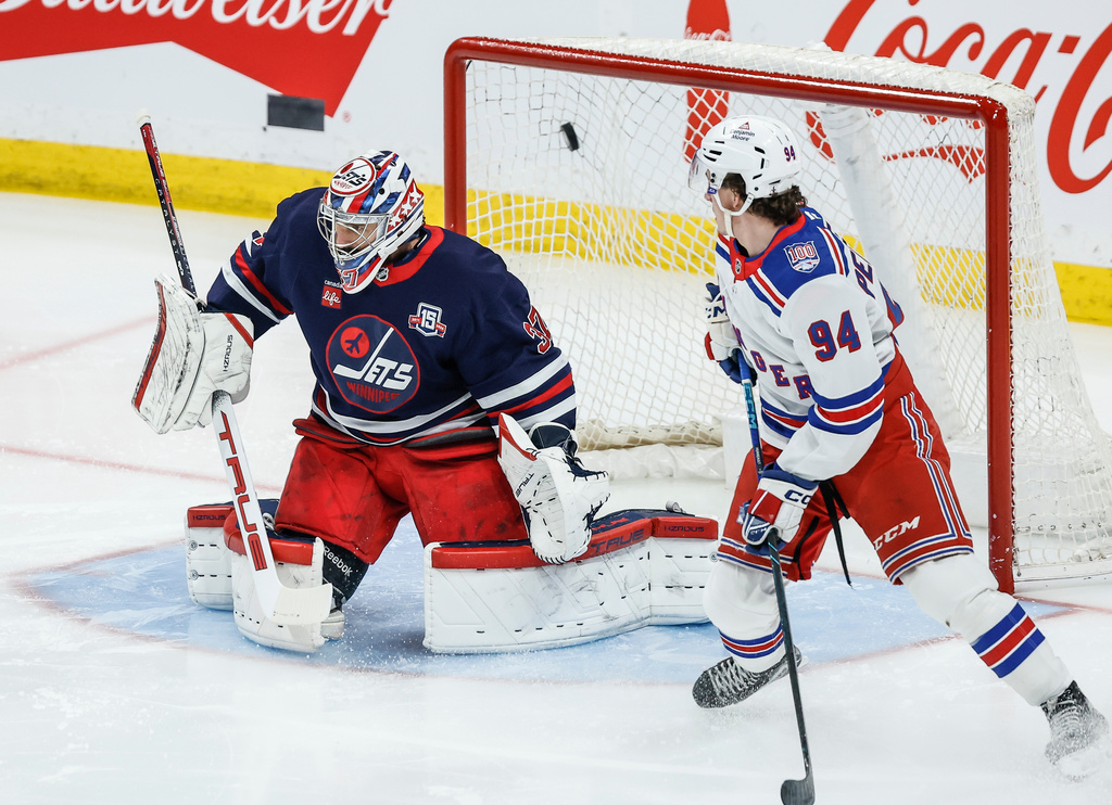 New York Rangers' Gabe Perreault (94) looks on as Adam Fox's (not shown) shot gets past Winnipeg Jets goaltender Connor Hellebuyck (37) during the first period of an NHL game in Winnipeg, Thursday, March 12, 2026. (John Woods/The Canadian Press via AP)