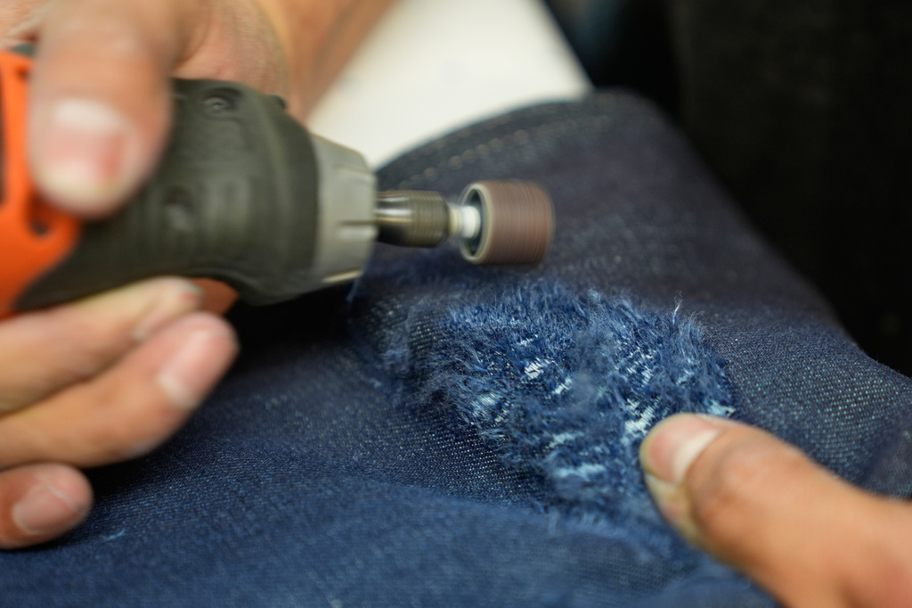 Bryan Morales Ibarra distresses denim by hand at the BPD Washhouse, a denim processing facility, in Jersey City, N.J., Tuesday, May 5, 2026. (AP Photo/Seth Wenig)