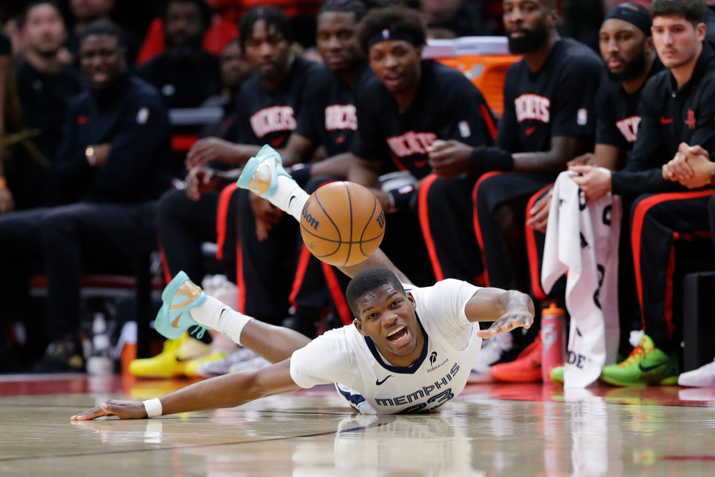 Memphis Grizzlies forward Cedric Coward reacts as he loses the ball after slipping on the court in front of the Houston Rockets bench during the first half of an NBA basketball game Monday, Jan. 26, 2026, in Houston. (AP Photo/Michael Wyke)