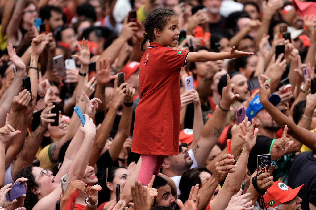 A girl standing on a man's shoulders reaches out amid a crowd of supporters of Brazilian President Luiz Inacio Lula da Silva, who is running for reelection, during his final campaign rally, a day ahead of the presidential runoff election in Sao Paulo, Brazil, Saturday, Oct. 24, 2026. (AP Photo/Natacha Pisarenko)