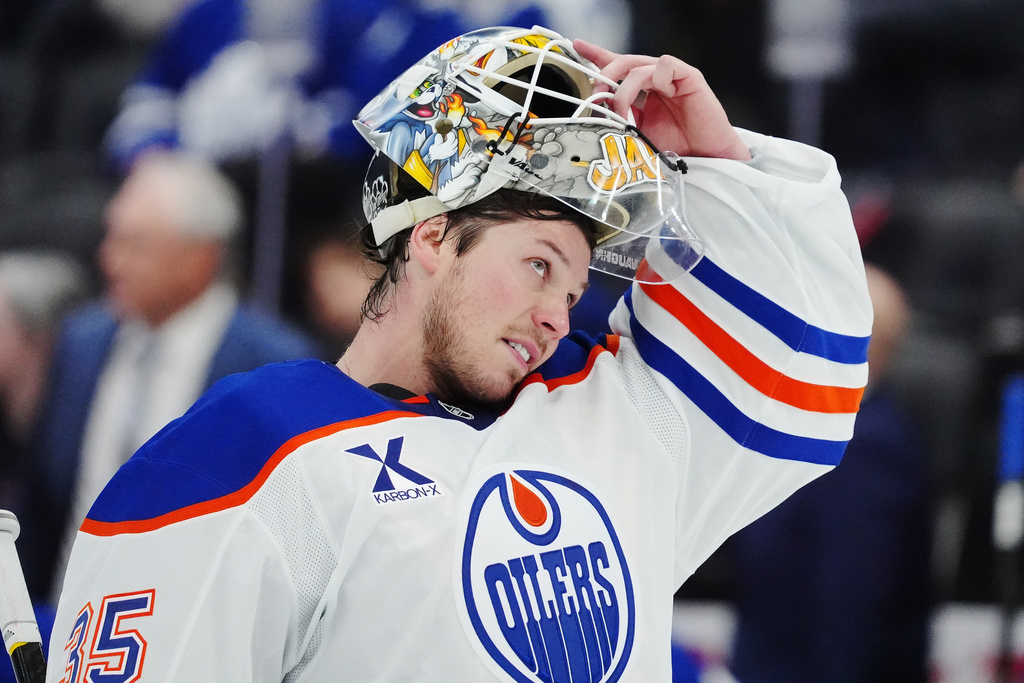 Edmonton Oilers goaltender Tristan Jarry (35) adjusts his mask during second period NHL hockey action in Toronto on Saturday, Dec. 13, 2025. (Frank Gunn/The Canadian Press via AP)