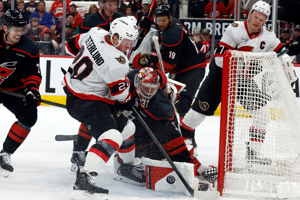 Carolina Hurricanes goaltender Frederik Andersen (31) blocks a shot by Ottawa Senators' Fabian Zetterlund (20) with Senators' Brady Tkachuk (7) looking on during the first period of Game 2 of an NHL hockey Stanley Cup first-round playoff series in Raleigh, N.C., Monday, April 20, 2026. (AP Photo/Karl DeBlaker)