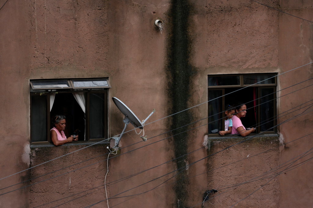 Residents watch firefighters and civil defense workers at the site of a landslide caused by heavy rains and severe flooding in the Parque Burnier neighborhood of Juiz de Fora in Minas Gerais state, Brazil, Tuesday, Feb. 24, 2026. (AP Photo/Silvia Izquierdo)