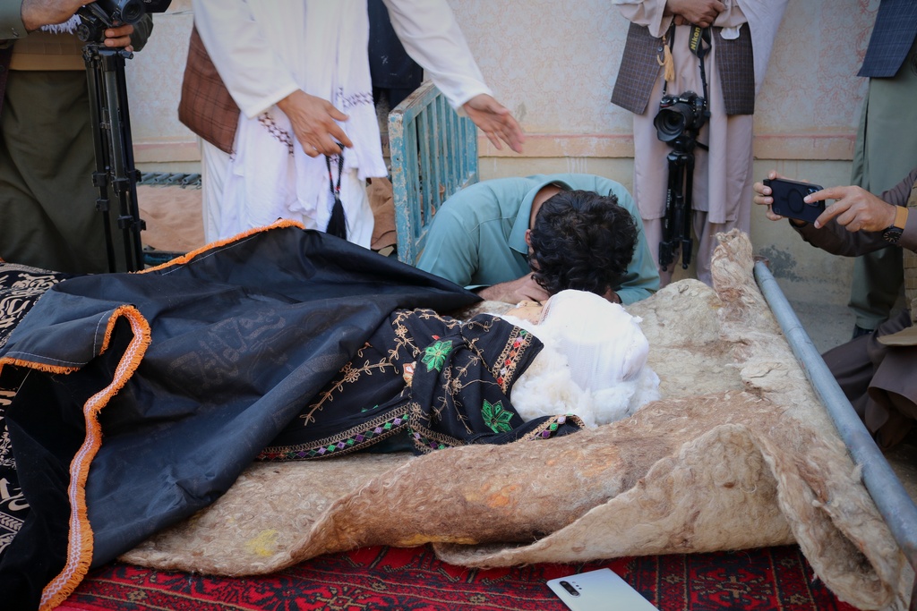 A man mourns next to the body of a child killed in a strike that hit a house in the Momand Dara district of Nangarhar province, Afghanistan, near the border with Pakistan, Friday, March 13, 2026. (AP Photo/Hedayat Shah)