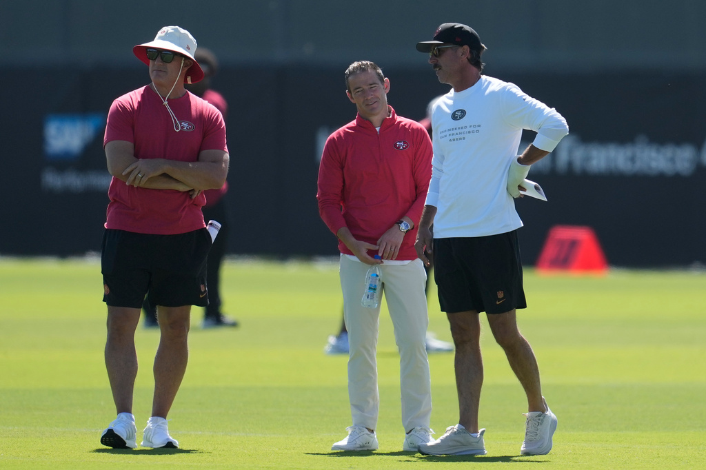 San Francisco 49ers general manager John Lynch, left, and head coach Kyle Shanahan, right, watch players run drills during the NFL football team's training camp, Monday, Aug. 3, 2026, in Santa Clara, Calif. (AP Photo/Jeff Chiu)