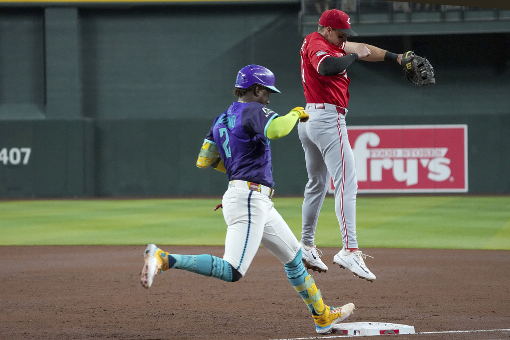 Arizona Diamondbacks' Geraldo Perdomo, left, beats the throw to first base after Cincinnati Reds first base Spencer Steer had to jump for the throw during the third inning of a baseball game Saturday, Aug. 23, 2025, in Phoenix. (AP Photo/Darryl Webb)