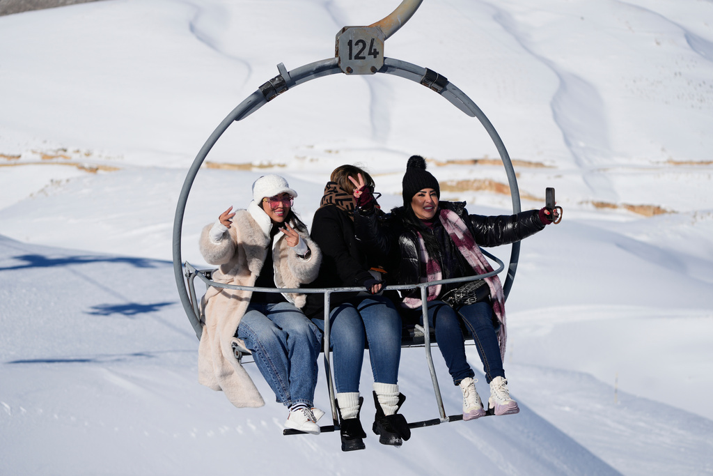 Tourists take selfies as they ride a chairlift at the Mzaar-Kfardebian ski resort northeast of Beirut, Lebanon, Saturday, Jan. 3, 2026. (AP Photo/Hassan Ammar)
