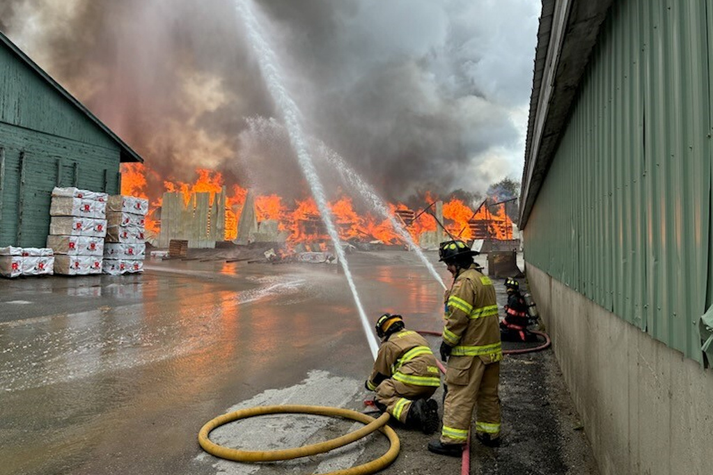 This photo provided by the Maine Department of Public Safety shows Firefighters try to extinguish flames from a large fire at Robbins Lumber in Searsmont, Maine on Friday, May 15, 2026 (Maine Department of Public Safety via AP)