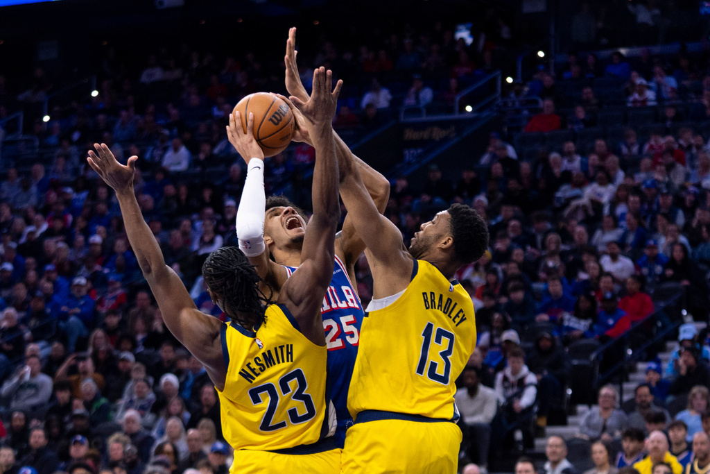 Philadelphia 76ers' Dom Barlow, center, goes up to shoot as he is fouled by Indiana Pacers' Tony Bradley, right, and defended by Aaron Nesmith, left, during the first half of an NBA basketball game, Monday, Jan. 19, 2026, in Philadelphia. (AP Photo/Chris Szagola)