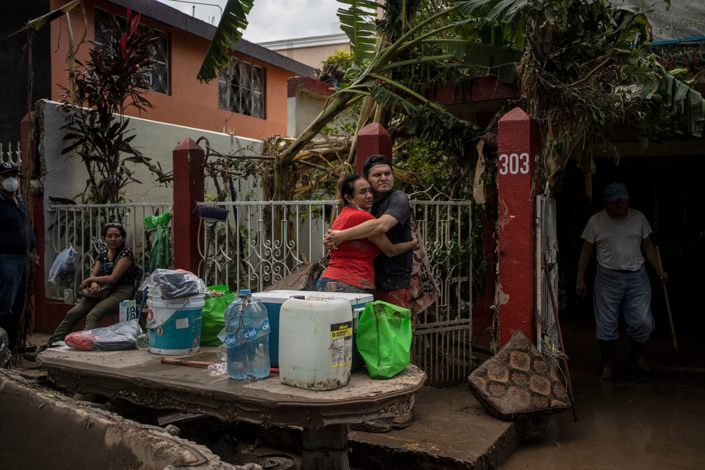 Locals embrace outside a flooded house in Poza Rica, Mexico, Sunday, Oct. 12, 2025, after widespread flooding and landslides. (AP Photo/Felix Marquez)