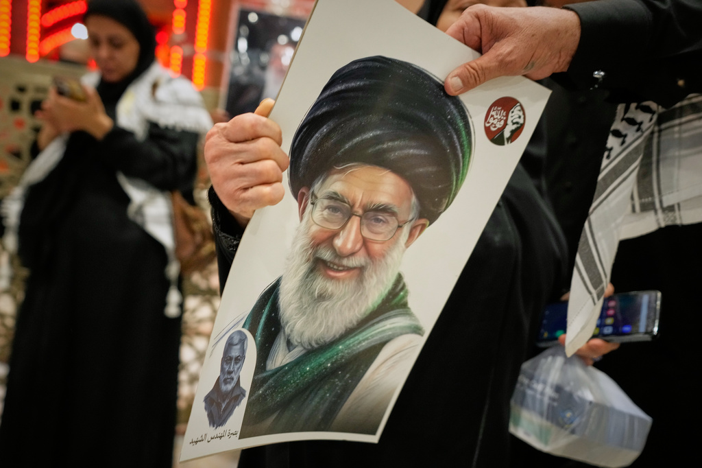 Portraits of the late Iranian Supreme Leader Ayatollah Ali Khamenei are distributed outside the Imam Ali Shrine on the eve of funeral ceremonies in Najaf, Iraq, Tuesday, July 7, 2026. (AP Photo/Hadi Mizban)