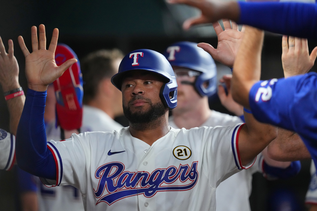 Texas Rangers' Elias DÌaz is greeted in the dugout after he and teammate Danny Jansen-, back, scored on a bases loaded single by teammate Corey Seager against the Boston Red Sox during the second inning of a baseball game Tuesday, Sept. 15, 2026, in Arlington, Texas. (AP Photo/Julio Cortez)