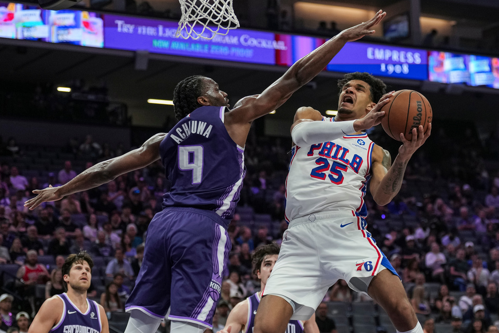 Philadelphia 76ers forward Dominick Barlow (25) goes for a layup against Sacramento Kings forward Precious Achiuwa (9) during the first half of an NBA basketball game, Thursday, March 19, 2026, in Sacramento, Calif. (AP Photo/Justine Willard)