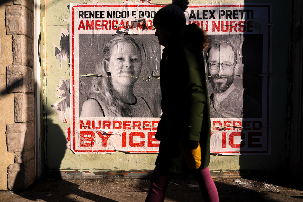 FILE - A woman walks by posters of Renee Good and Alex Pretti during a solidarity bike ride for Pretti, Jan. 31, 2026, in Minneapolis. (AP Photo/Julia Demaree Nikhinson, File)