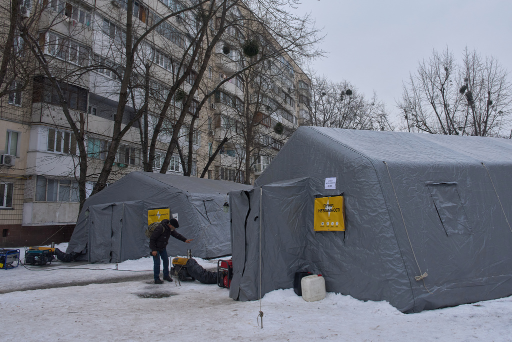 A man gets warm at emergency tents where people can warm up following Russia's regular air attacks against the country's energy objects, that leave residents without power, water and heating in the dead of winter, in Kyiv, Ukraine, Tuesday, Jan. 13, 2026. (AP Photo/Efrem Lukatsky)