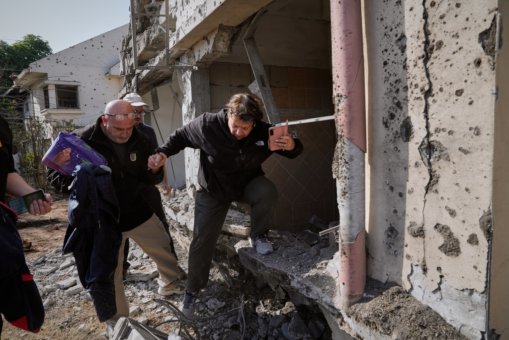 A woman gathers belongings from her family's home after it was damaged by a projectile launched from Lebanon, in Haniel, central Israel, Thursday, March 12, 2026. (AP Photo/Baz Ratner)