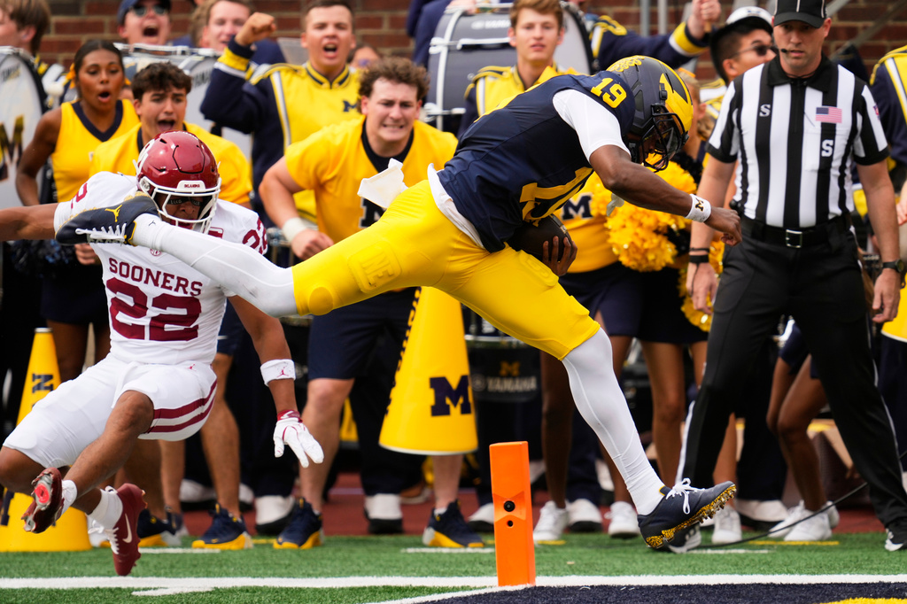 Michigan quarterback Bryce Underwood (19) scores on a 38-yard touchdown run as Oklahoma defensive back Peyton Bowen (22) defends in the first half of an NCAA college football game Saturday, Sept. 12, 2026, in Ann Arbor, Mich. (AP Photo/Paul Sancya)